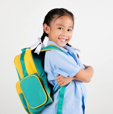 Portrait smiling Asian little girl kindergarten with schoolbag crossed arms studio shot isolated white background, good job feedback, happy woman kid in pigtails wearing school uniform, back to school